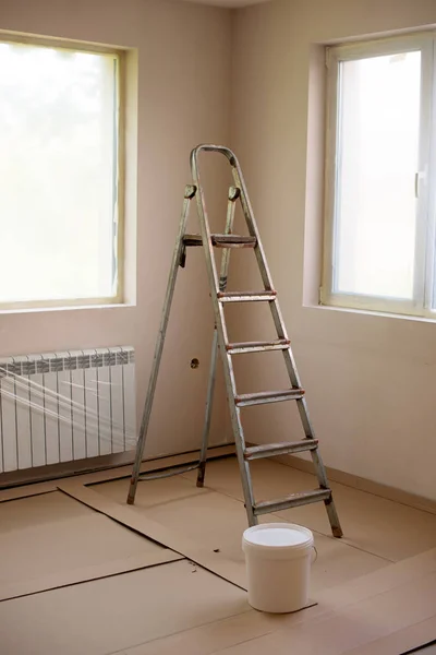 Painting walls in room with roller and ladder during renovation