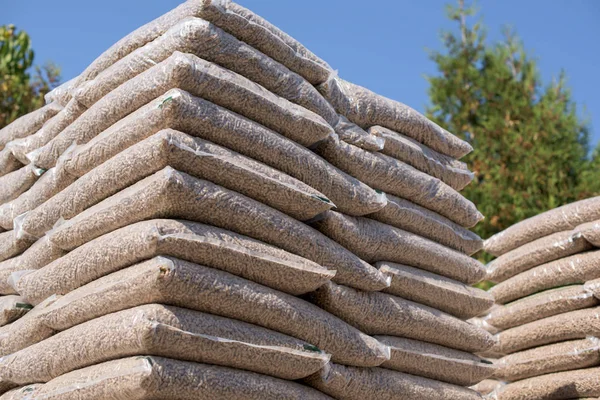 Piles of plastik bags full with wooden pellets arranged in rows — Stock Photo, Image