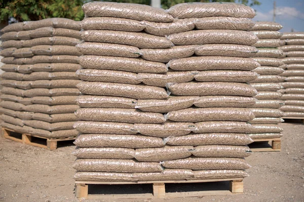 Pilas de bolsas de plástico llenas de pellets de madera en filas y colu —  Fotos de Stock