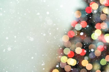 Mavi arka plan ve kar tanelerinde bulanık Noel ağacı ışıkları süslemesi