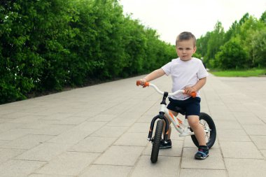 Küçük çocuk bir bisiklet üzerinde. Hareket, bir yolda yakalandı. Okul öncesi çocuğun ilk gün bisiklet. Hareket sevinç. Bir bisiklet sürme sırasında dengesini korumak küçük atlet öğrenir.