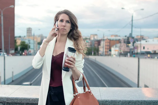 Güzel kadın sokakta yürürken telefonda konuşuyor. Cep telefonu ofisinin çağırma. Kadın iş tarzı.