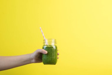Smoothie shake renkli duvara tutan kadın el. Yeşil sağlıklı güler yüzlü kavramı içme. Yaz