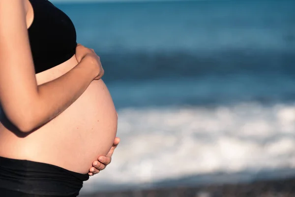 腹部的孕妇与手在海上背景 — 图库照片