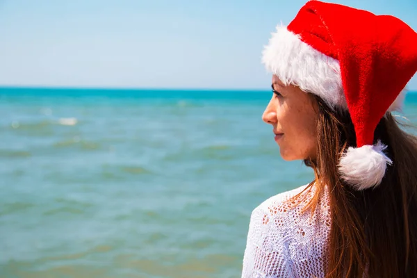 热带海滩上戴着圣诞老人帽子的年轻女子 圣诞假期 圣诞节海滩旅行妇女穿着圣诞老人的帽子和比基尼在热带海滩上享受圣诞节 戴着圣诞老人帽子和比基尼的女人 — 图库照片