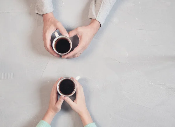 Закохана пара тримає руки з кавою на білому мармуровому столі. Фотографії, зроблені зверху, вид зверху з пробілом для копіювання — стокове фото