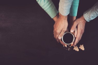 Noel ışıkları ile siyah tabloda kahve ile el ele tutuşarak aşk çift. Kopya alanı yukarıdan çekilmiş, en iyi manzaralı fotoğraf