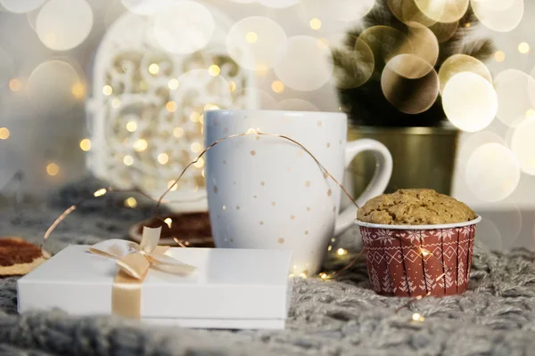 Зимний натюрморт из шарфа, белая кружка какао, кофе или горячий шоколад, кекс, рождественская елка на теплой клетке с гирляндой . — стоковое фото