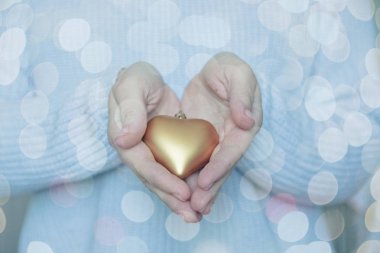 Kadın elele bir kar kış arka planda bir güzel parlak altın kalp. Aşk ve St. Valentine rahat kavramı.