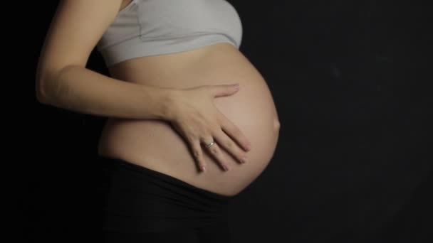 Zwangere vrouwen strelen haar buik slowmotion donkere backround — Stockvideo