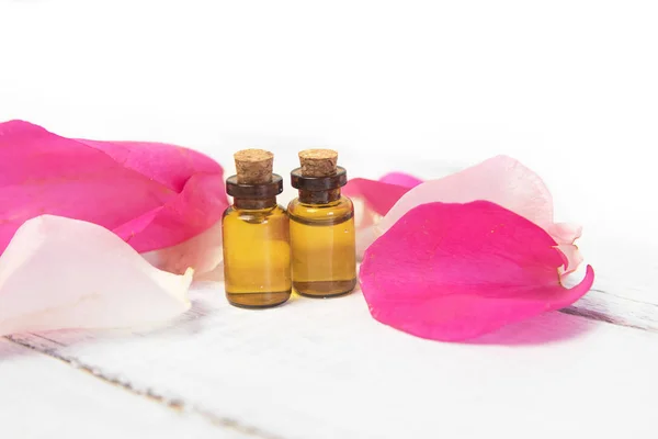 Aceite esencial con pétalos de rosa sobre fondo de madera con copyspace. Aromaterapia spa productos a base de hierbas — Foto de Stock