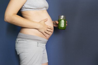 gebelik, insanlar ve dinlenme kavramı - mutlu hamile Afrikalı-Amerikalı kadın yeşil sebze suyu ya da iki yüzlü evde içme