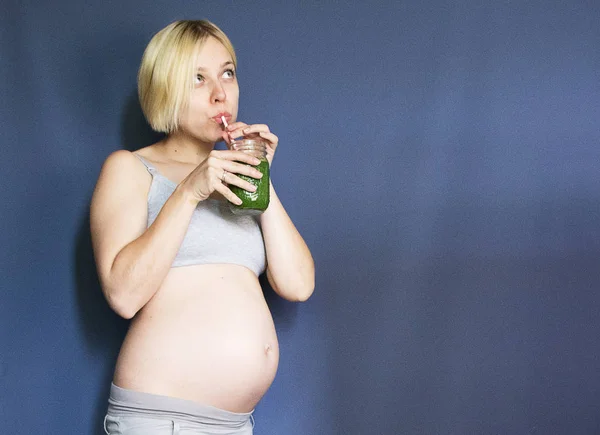 Grossesse, personnes et concept de repos - heureuse femme africaine américaine enceinte buvant du jus de légumes verts ou un smoothie à la maison — Photo