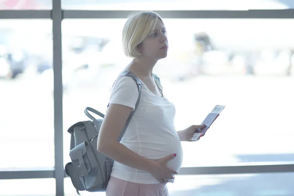 Gravid kvinna resor av planet står nära fönstret — Stockfoto