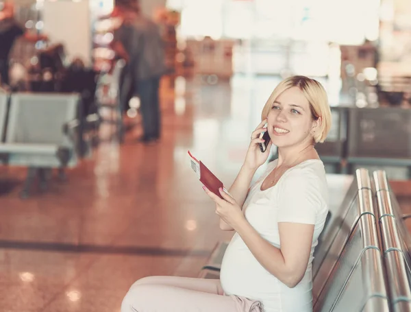 Беременная женщина летит на самолете, сидя за столом и разговаривая по телефону . — стоковое фото