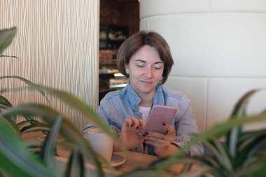 İstemci ile telefonla konuşmayı kafede oturan güzel üst düzey iş kadını. Kahve dükkanında otururken kadın iş cep telefonu üzerinde profesyonel konuşurken Olgun.