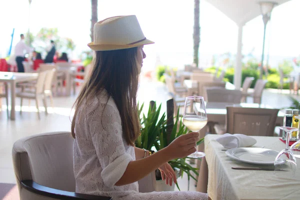 Jonge vrouw drinken van witte wijn op het terras in de openlucht kijken op van de Middellandse Zee. Vrouw in wit sundress op zomervakantie Europa reizen in Albanië — Stockfoto