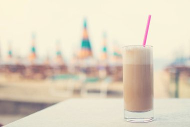 Sıcak kahve ve su deniz arka plan ile cam bardak.