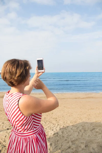 Путешествия, лето, технологии и люди - сексуальная молодая женщина делает селфи со смартфоном на пляже — стоковое фото