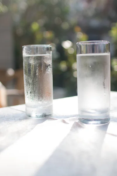 two glasses of water on a wooden board