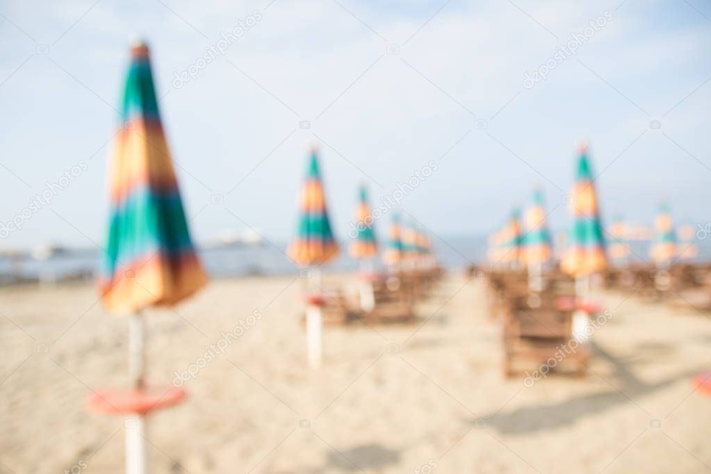 Aerial view to sandy beach of Adriatic sea in Albania, full of umbrellas and sunbeds, Port of Durres in horizon.