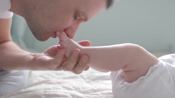 Nära upp skott far kyssar fötter baby — Stockvideo