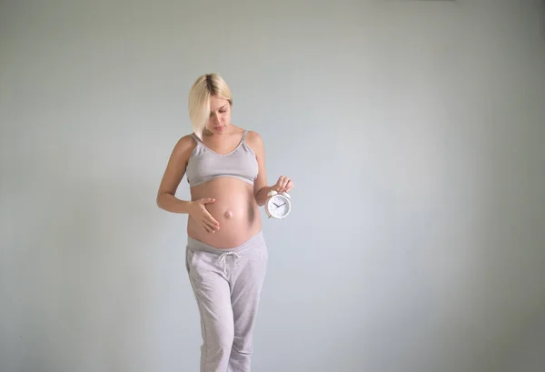 Portret van verbaasd zwangere vrouw houden Wandklok — Stockfoto