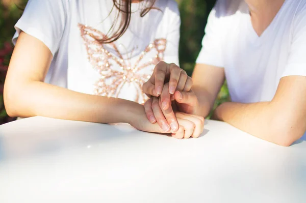 A couple is sitting in a cafe at the table. A man holds a girls hand. — Stock Photo, Image