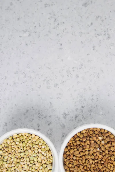 Zelené pohanky a obyčejných buchwheat šedá tabulka v bílé míse — Stock fotografie