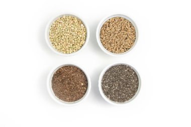 Beyaz arka plan üzerinde izole farklı kabuğu çıkarılmış tane topluluğu. Buğday, chia, keten, amaranth, mercimek, kuskus, buğday kase üstten görünüm.
