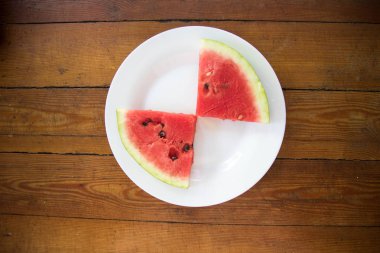 Kase ve beyaz plaka üzerinde dilim karpuz parçalar. Üstten görünüm