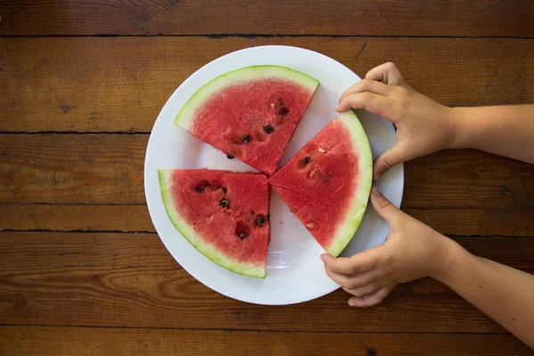 Plátek vodního melounu v dětské ruce, zblízka — Stock fotografie