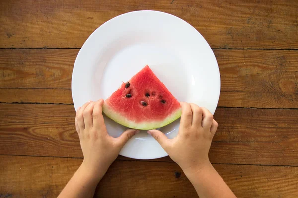 Plátek vodního melounu v dětské ruce, zblízka — Stock fotografie