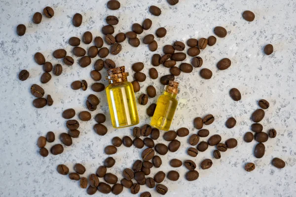 Kávé illóolaj üvegben, kávébab, a szürke háttér — Stock Fotó