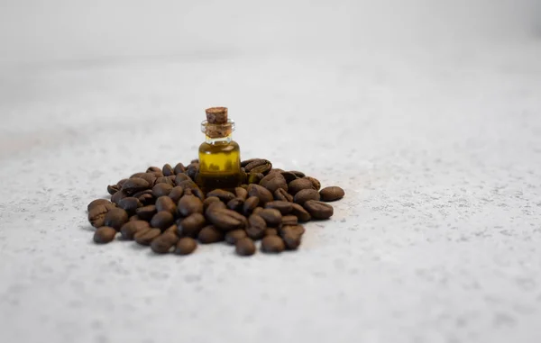 Kávé illóolaj üvegben, kávébab, a szürke háttér — Stock Fotó