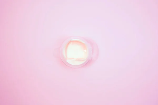 Recipiente de crema cosmética sobre fondo rosa desde la vista superior — Foto de Stock