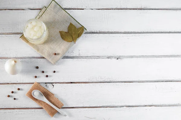 Pot en verre d'oignons marinés sur fond de bois blanc — Photo