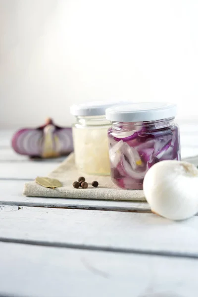 Pot en verre d'oignons marinés sur fond de bois blanc — Photo