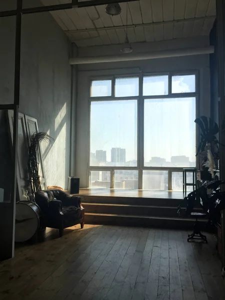 Gran ventana de metal-plástico negro en la pared. Desde la ventana el sol brilla intensamente. Primavera o mañana de verano. La ventana brilla la luz del sol . —  Fotos de Stock