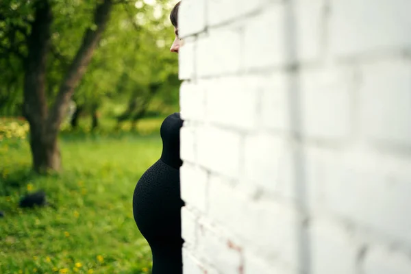 From behind the wall peeping belly of a pregnant woman in a black dress — Stock Photo, Image