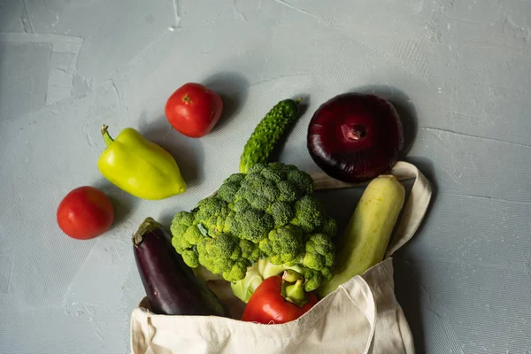 Set of products in a cotton eco bag on a marble table, eggplant, broccoli, tomatoes, peppers, zucchini. The concept of zero waste. — Stock Photo, Image