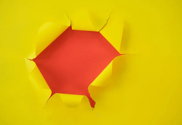 Papel amarillo rasgado sobre un fondo rojo — Foto de Stock