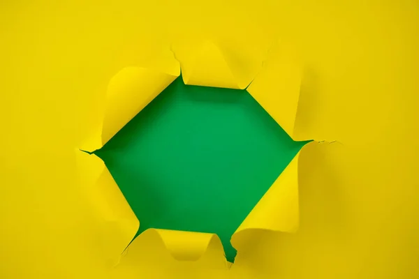 Papel amarillo rasgado sobre un fondo verde — Foto de Stock