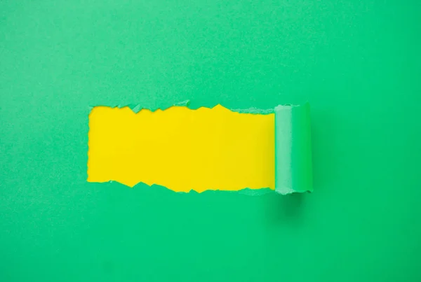 Papel verde desgarrado sobre un fondo amarillo — Foto de Stock