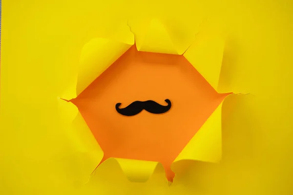 Papel amarillo rasgado contra un fondo naranja con bigote — Foto de Stock