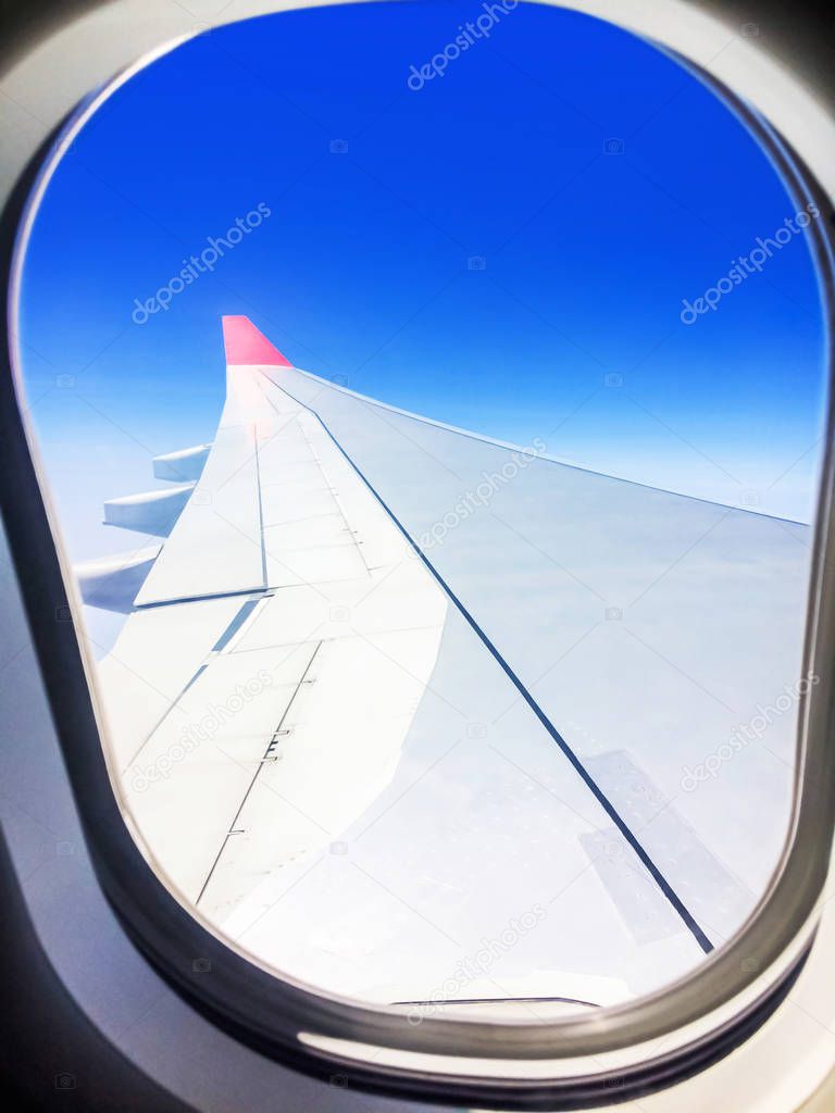 View of a commercial aeroplane from window where you can see the wing which flies above the clouds at height 35,000 feet.