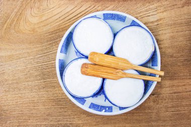 Tay Hindistan cevizi sütü muhallebi bir Tay tatlı pirinç unundan yapılmış, Hindistan cevizi sütü ve şekeri küçük seramik bardak yerine koymak bir ahşap zemin üzerinde. Khanom Thuai