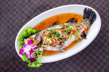 Deri yere ızgara desen beyaz seramik tabak koyun limon ile levrek balık buğulama. Üstten Görünüm.