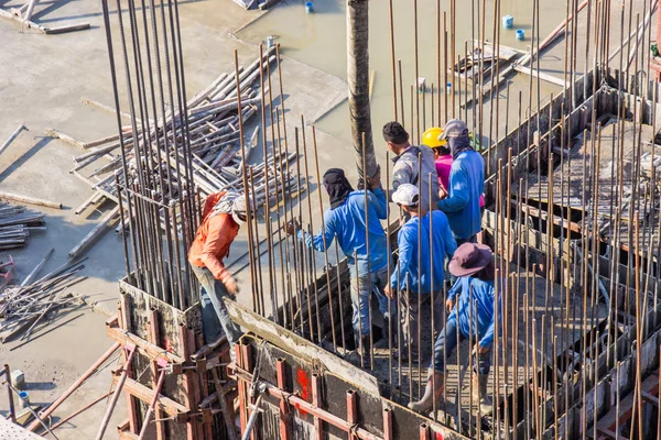 Cementet öntő munkások az építkezés területén az alapokba és pillérekbe zsaluzva. — Stock Fotó