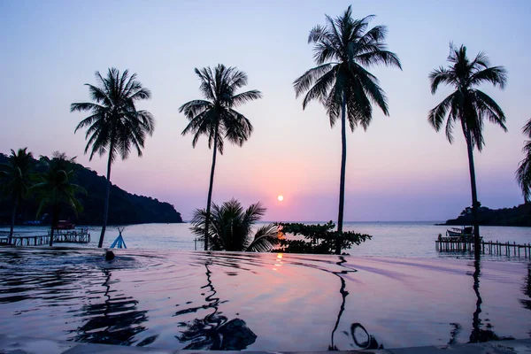 Puesta de sol que refleja en la superficie del agua en primer plano con árboles de coco área ao bang bao en la isla de Koh Kood es un distrito de la provincia de Trat . — Foto de Stock